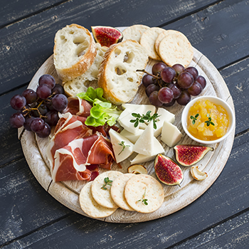 charcuterie platter with sliced bread, meat, cheese, and fruit