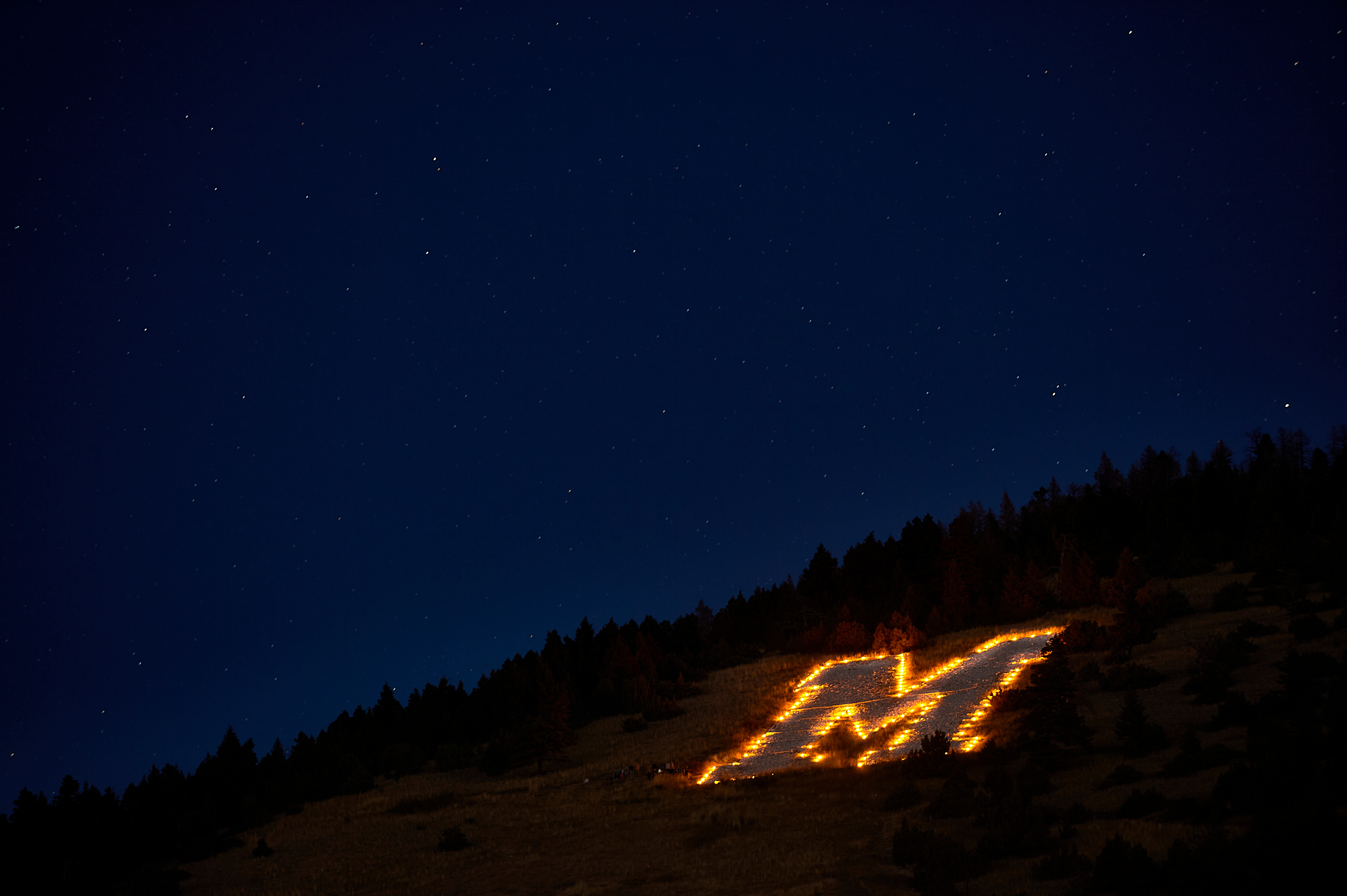 lit up "M" photo of the "M" on a hill in Bozeman, lit up at night