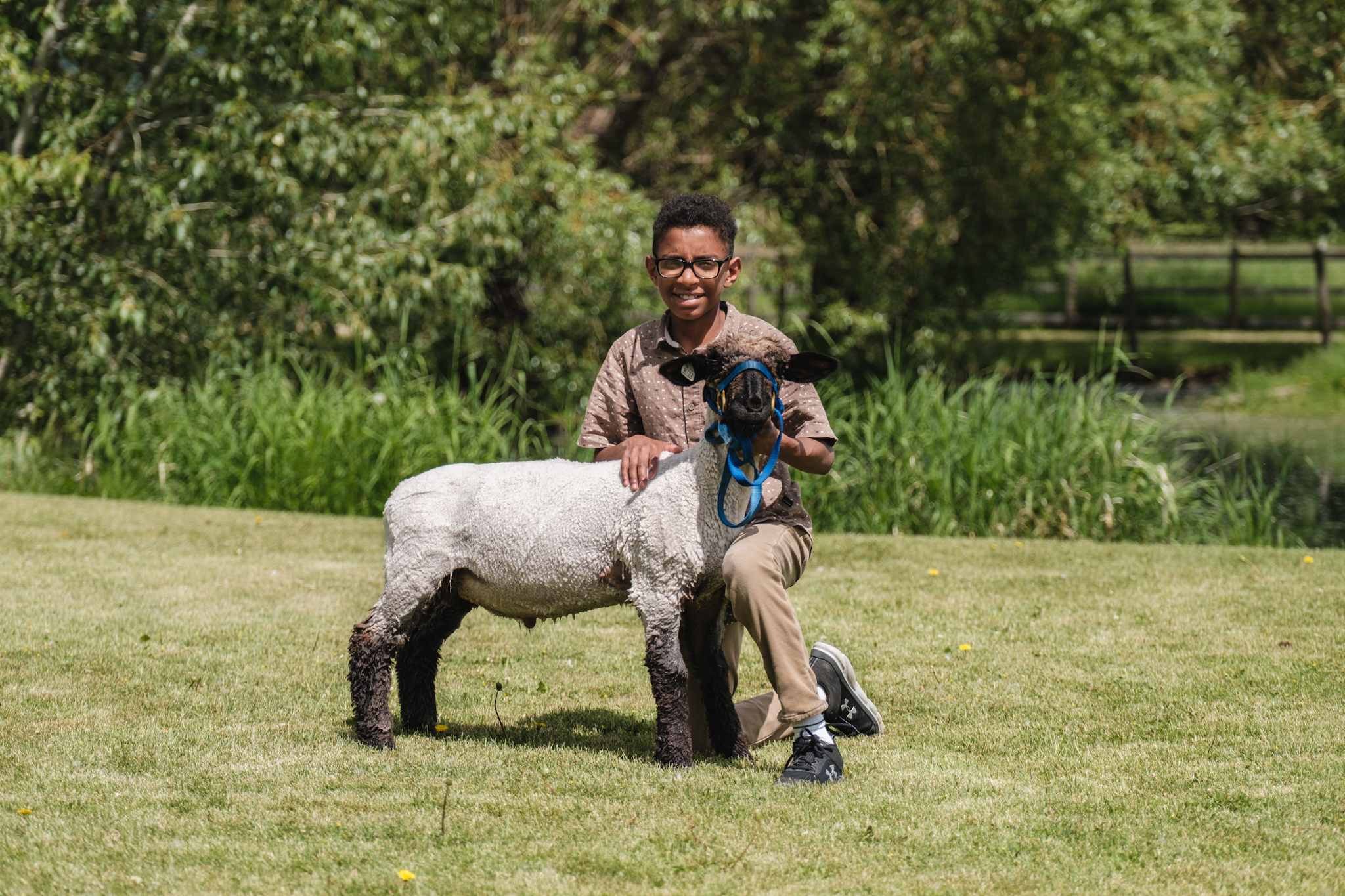 a young boy kneeling with his lamb