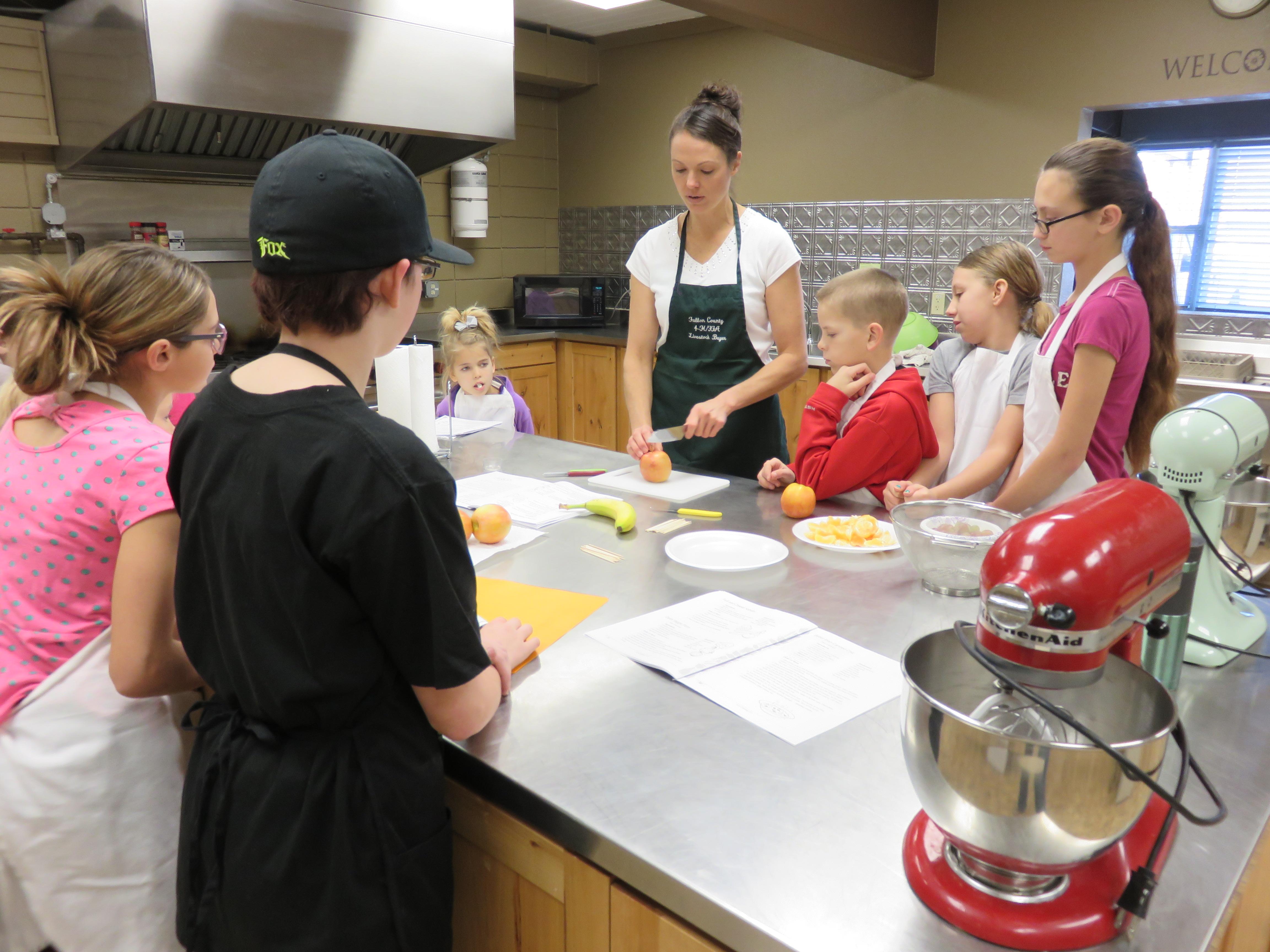 4-H members and volunteer cook together A female volunteer leads youth in a cooking project.