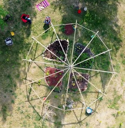A drone image looking down onto a structure of poles over Newah's Garden