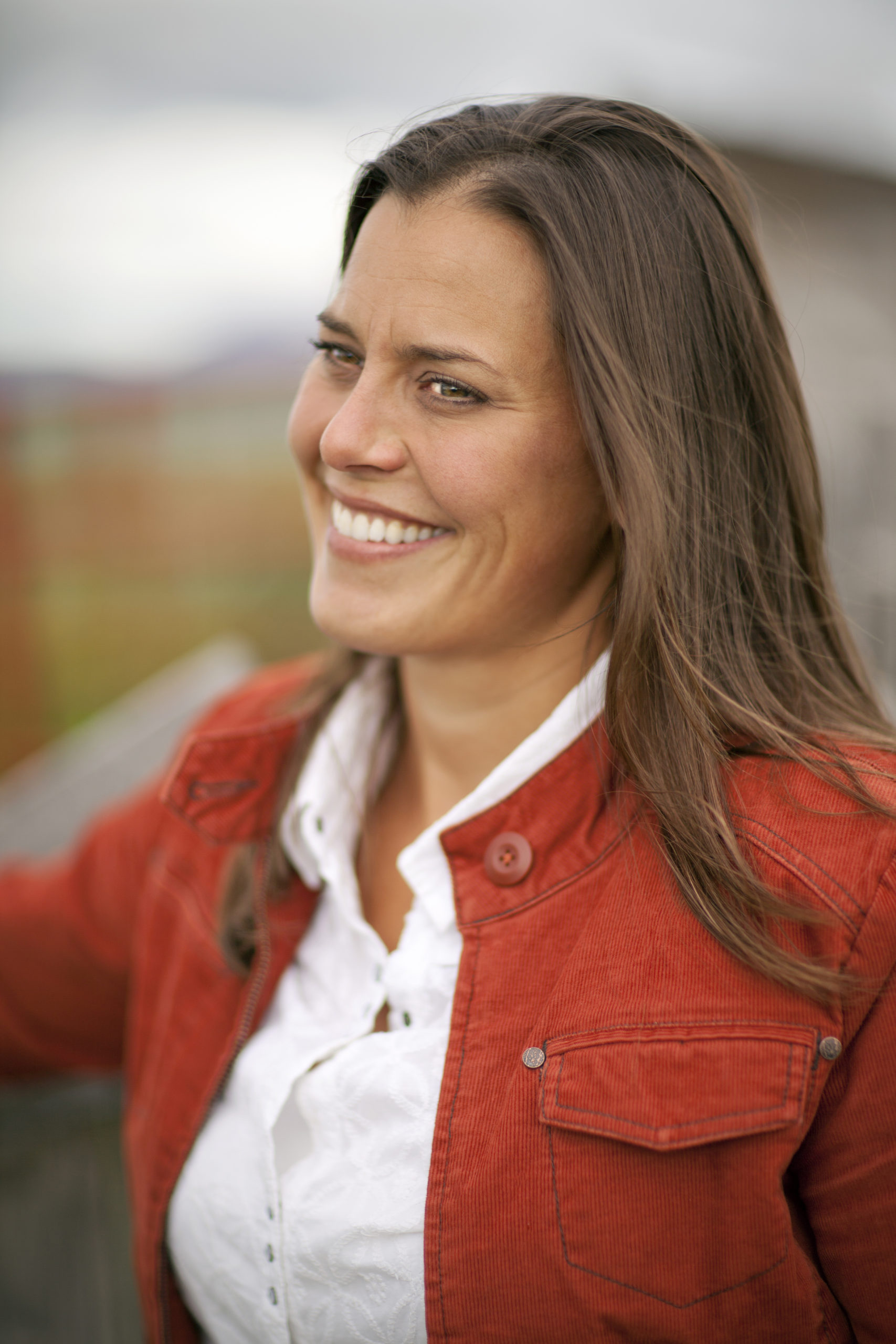 Sarah Calhoun Sarah Calhoun smiling in a red corduroy jacket with a white collared shirt underneath