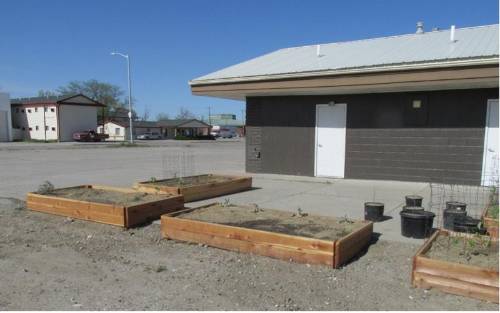 Raised garden beds a the Hardin Food Bank. Raised garden beds sit in the gravel parking area outside a building.