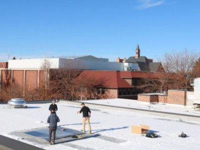 Students using tools to map the amount of snow on a roof top.