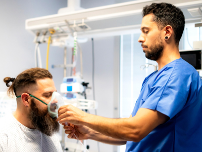 Surgical Technology Degree A respiratory therapist attaches a breathing device to a patient's face.